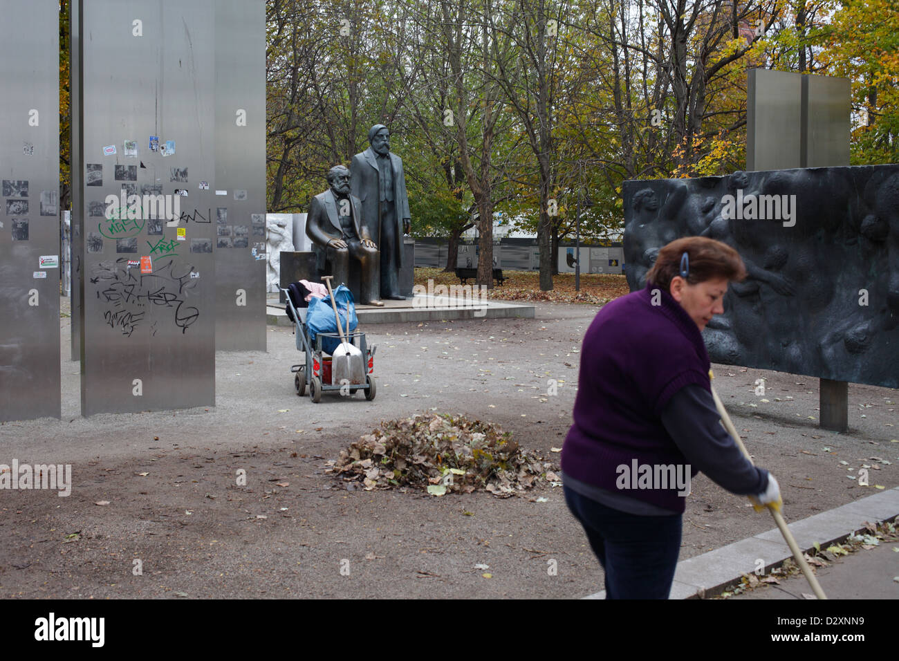 Berlin, Germany, woman raking leaves on a provisional converted Marx-Engels monument Stock Photo