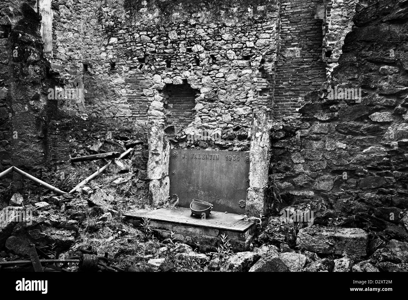 Interior of ruined house in Oradour-sur-Glane, France. All thats left are some walls and a fireplace and cooking pot. Stock Photo