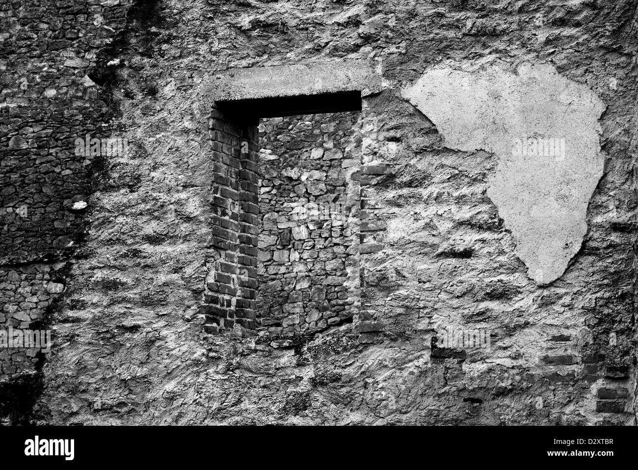 Damaged brick and stone wall and window, black and white showing lots of textures Stock Photo