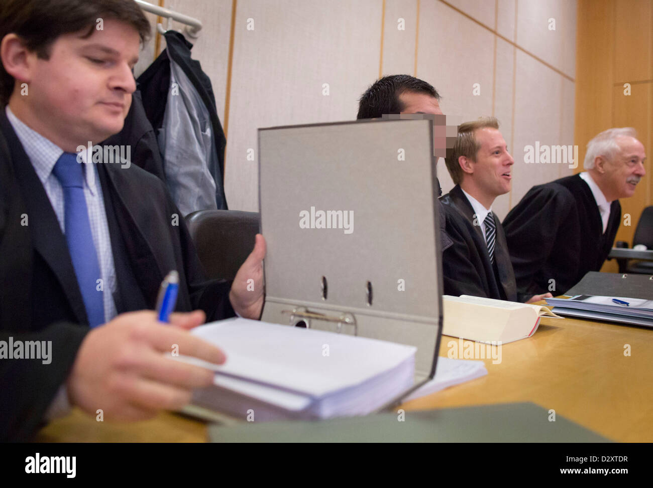The defendant (2-L) sits concealed by a file next to his attorneys Alexandros Tsioupas (L), Julian Tietze (2-R) and Christian Tietze (R) in the courtroom of the Land court in Frankfurt/Main, Germany, 04 February 2013. He is accused of having prepared an attack. The 26-year-old Afghan was injured badly when dynamite exploded in his appartment. Photo: Frank Rumpenhorst Stock Photo