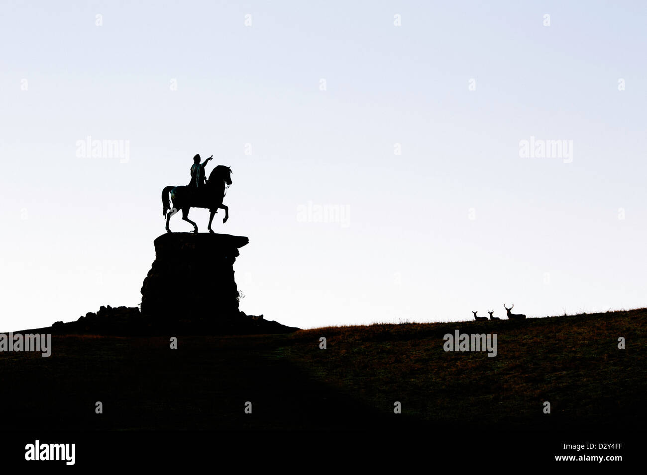 A silhouette of the copper horse  in Windsor Great Park with 3 deer below the statue. Stock Photo