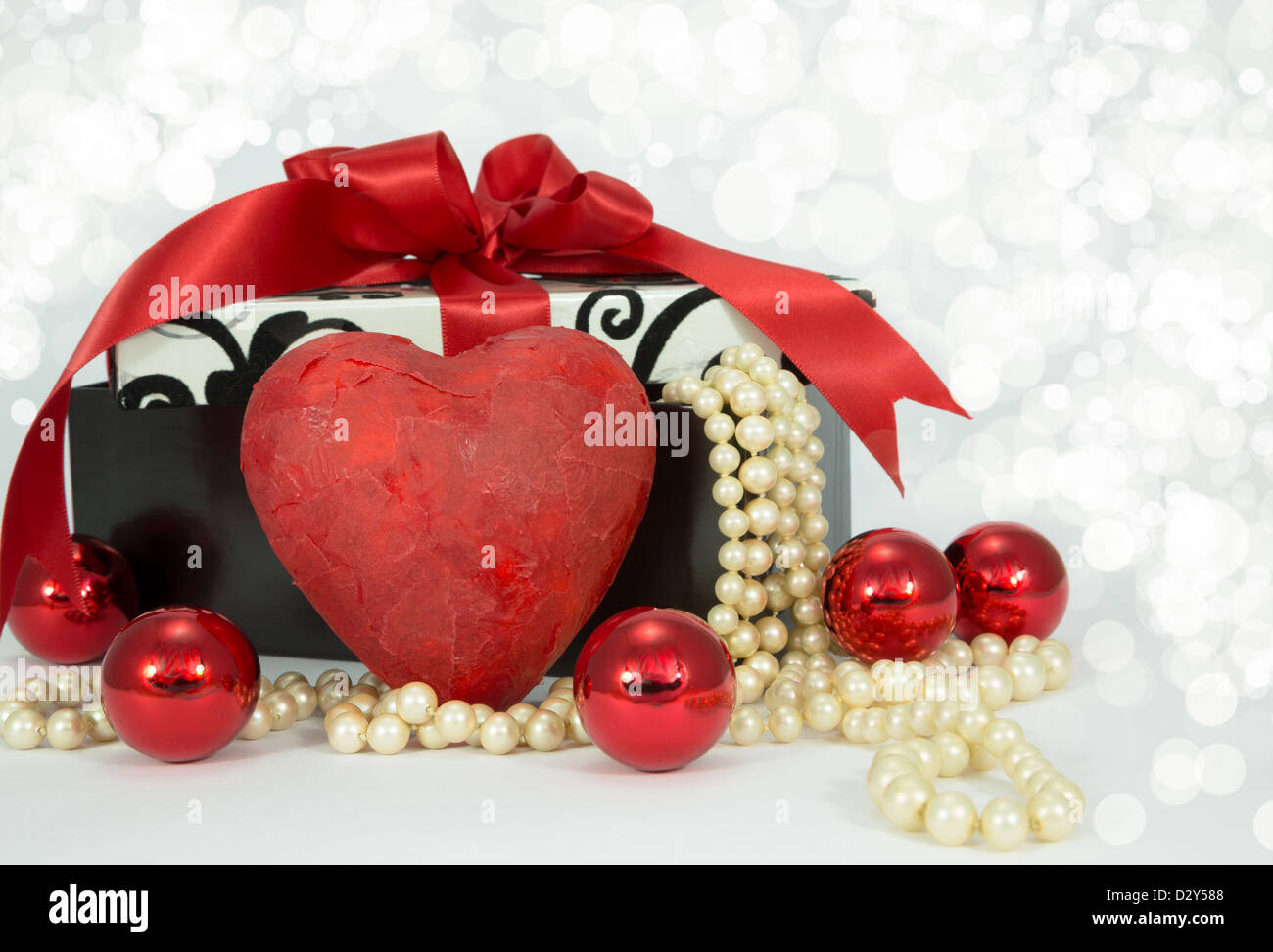 Red heart in front of a gift box with pearls flowing out of it with ...
