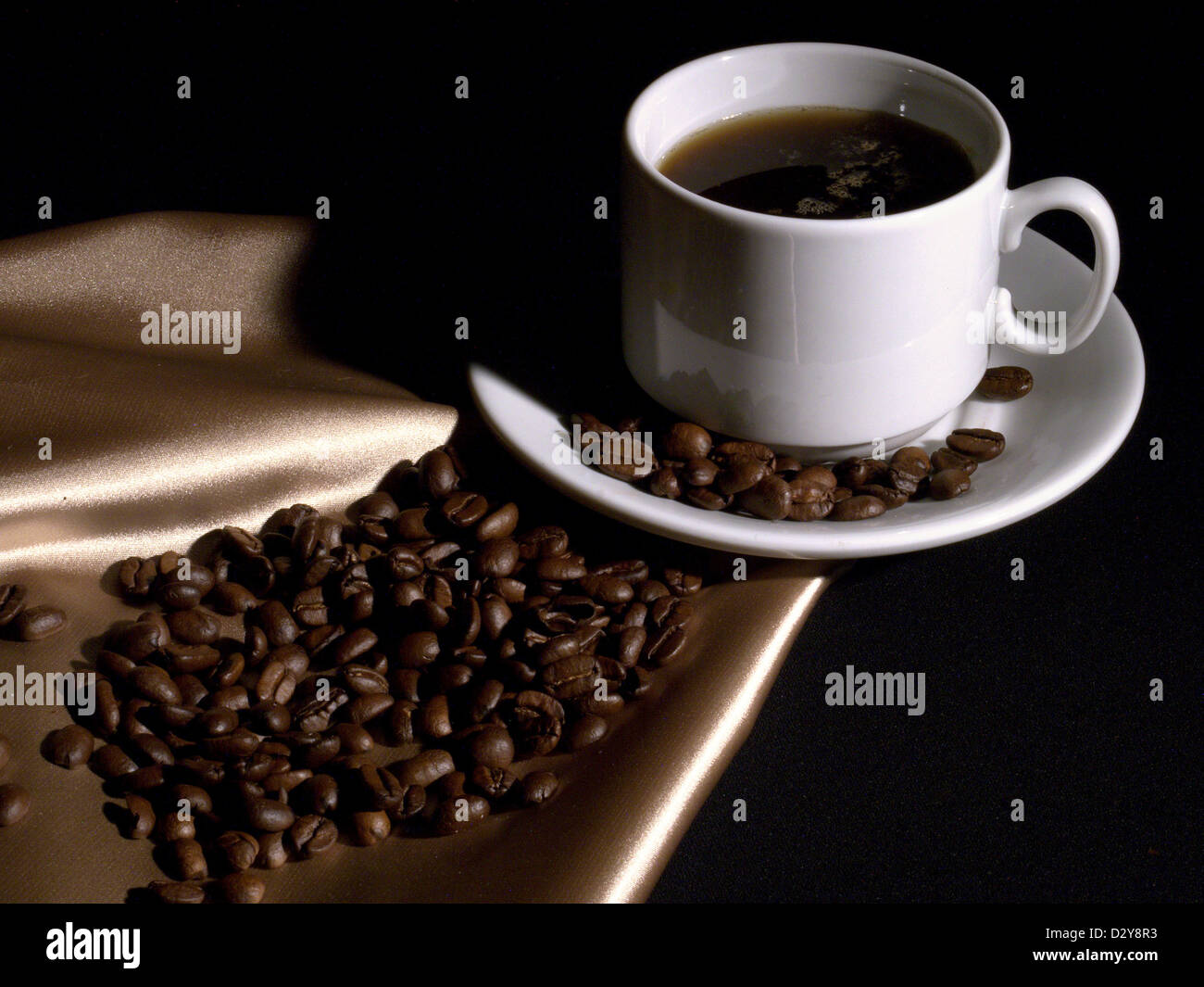 Cup of coffee and coffee beans on the golden fabric Stock Photo