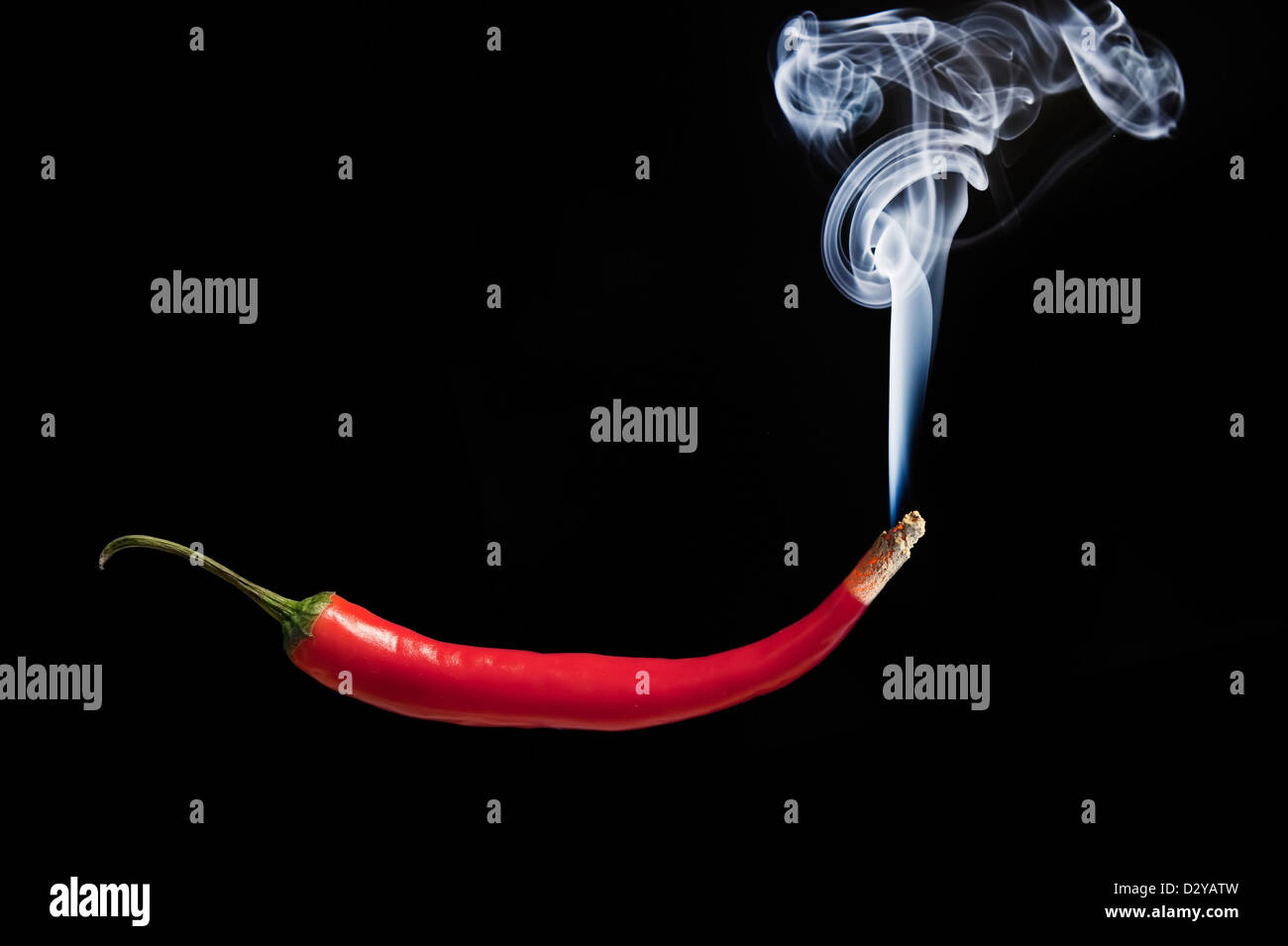 Red hot chilli pepper with smoke coming out of tip which is burning and
