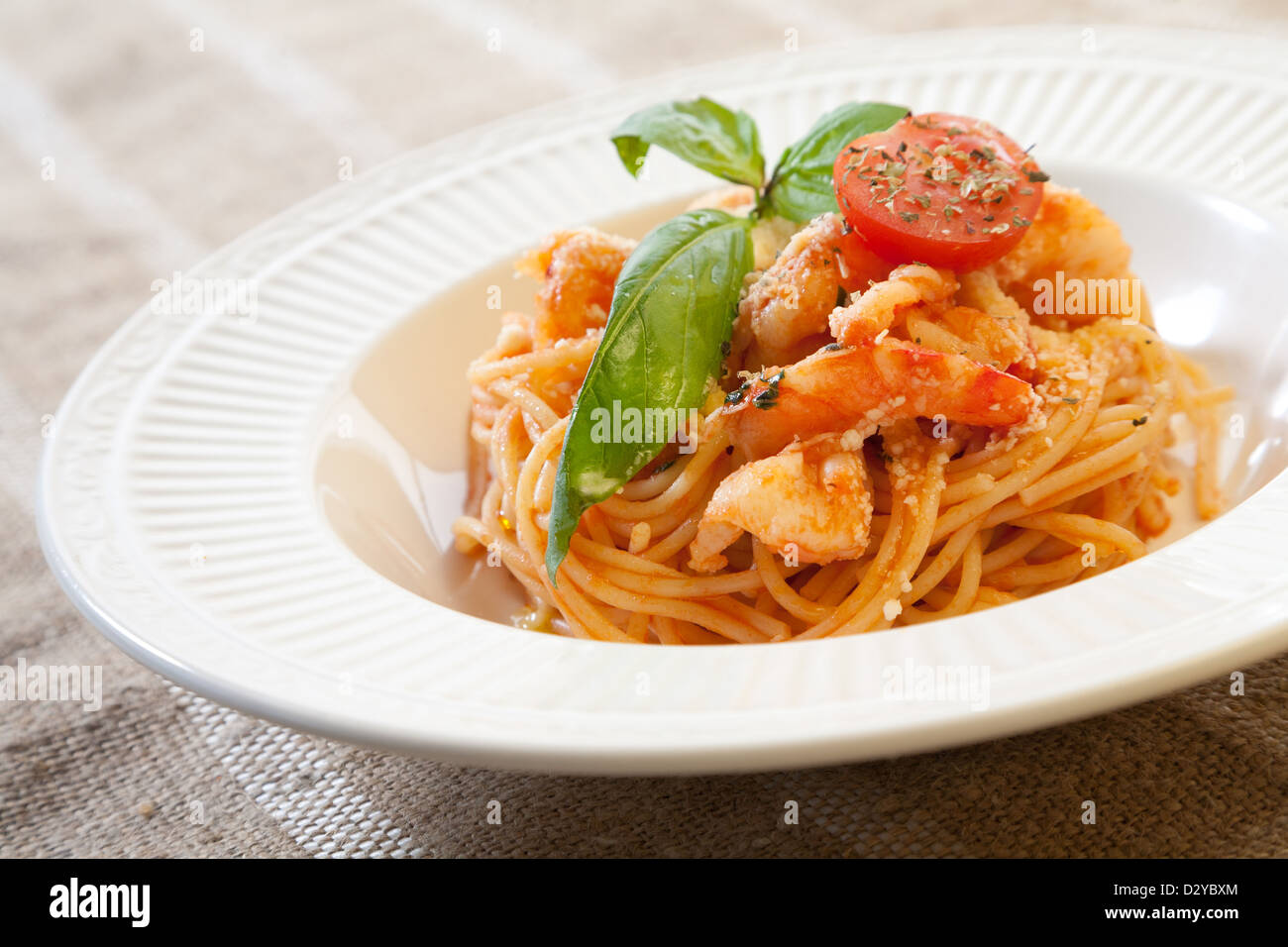 Pasta with shrimps and tomato sauce decorated with basil leafs and cherry tomato Stock Photo