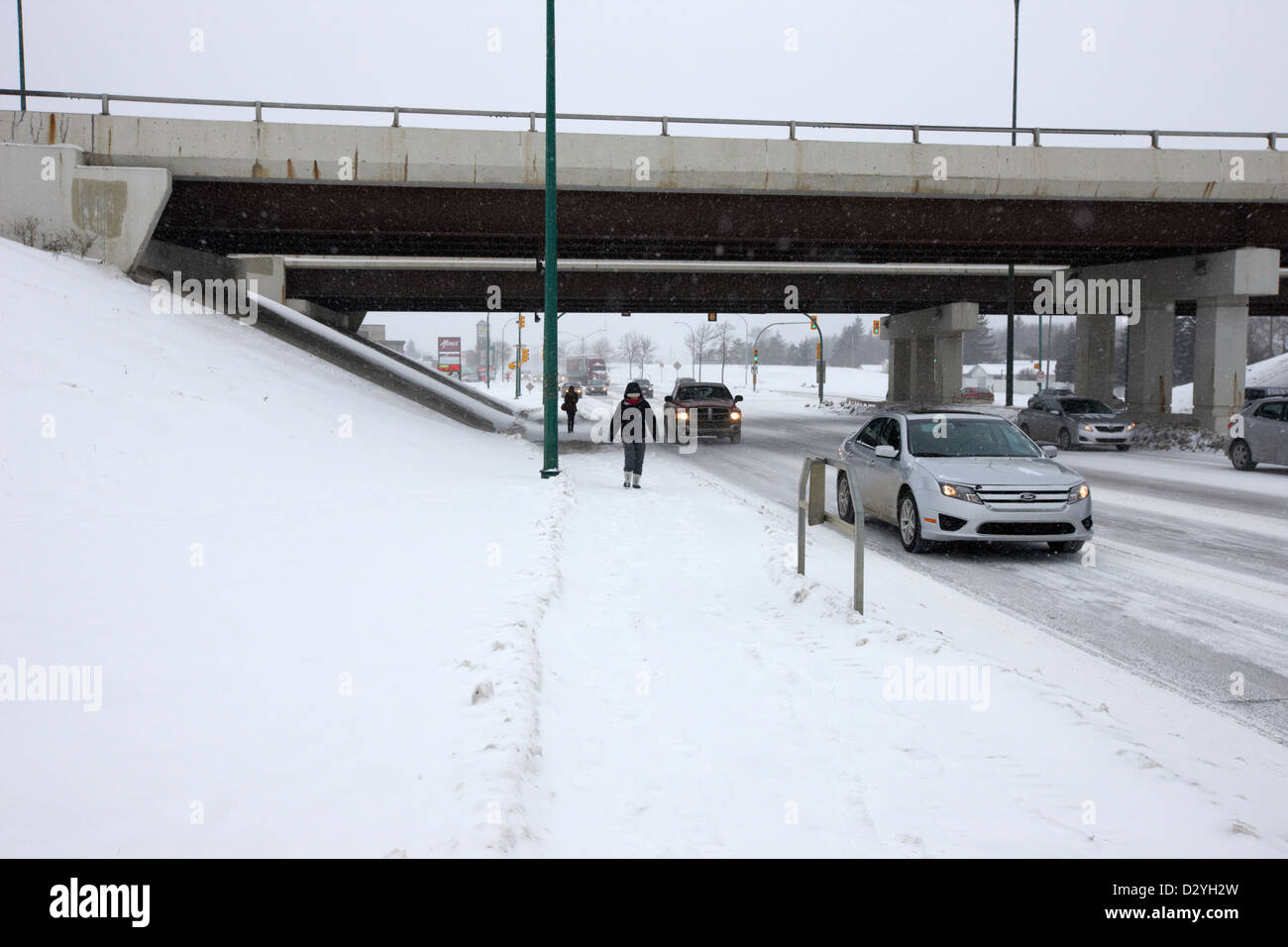 people walking and cars travelling along 8th street below circle drive underpass Saskatoon Saskatchewan Canada Stock Photo