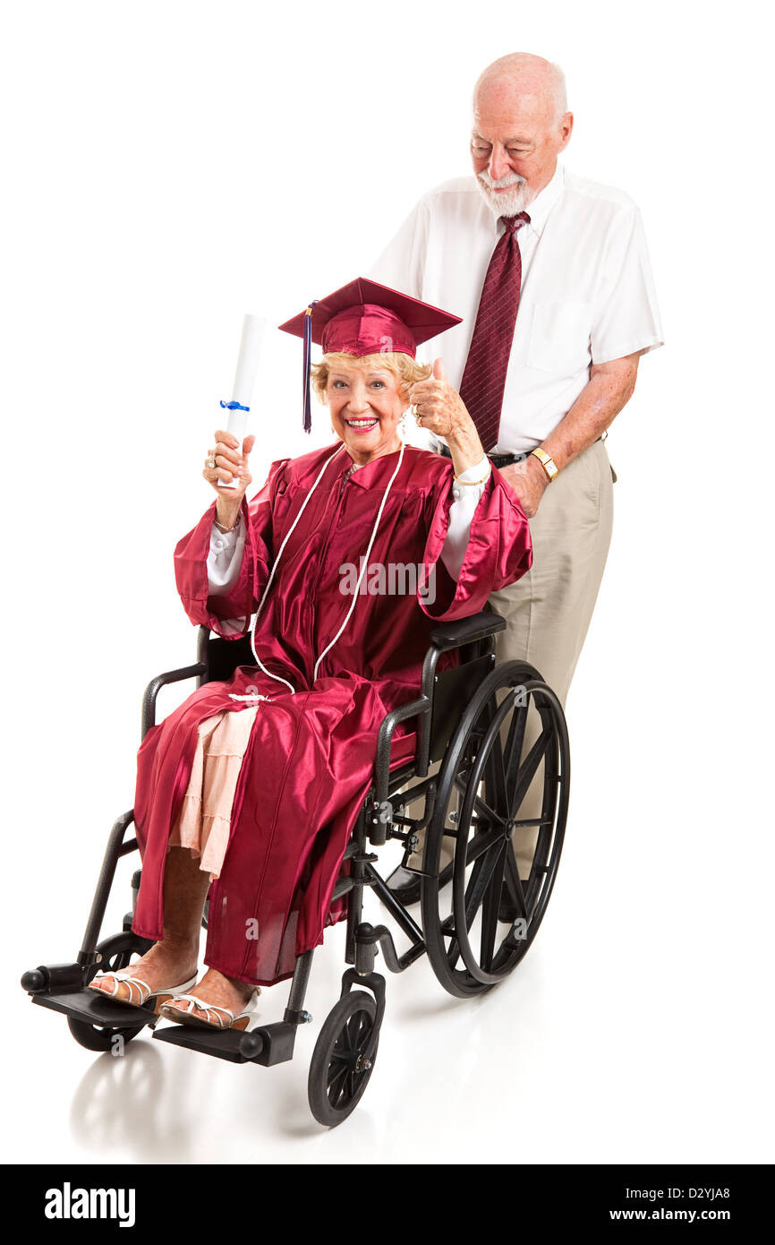 Disabled senior lady graduate gives a thumbs up as her husband pushes ...