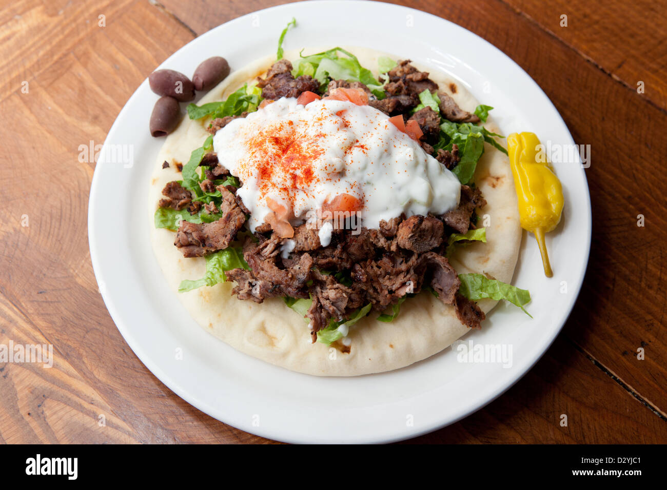 A single serving of Mediterranean style, home made lamb gyro, topped with lettuce, tahini sauce