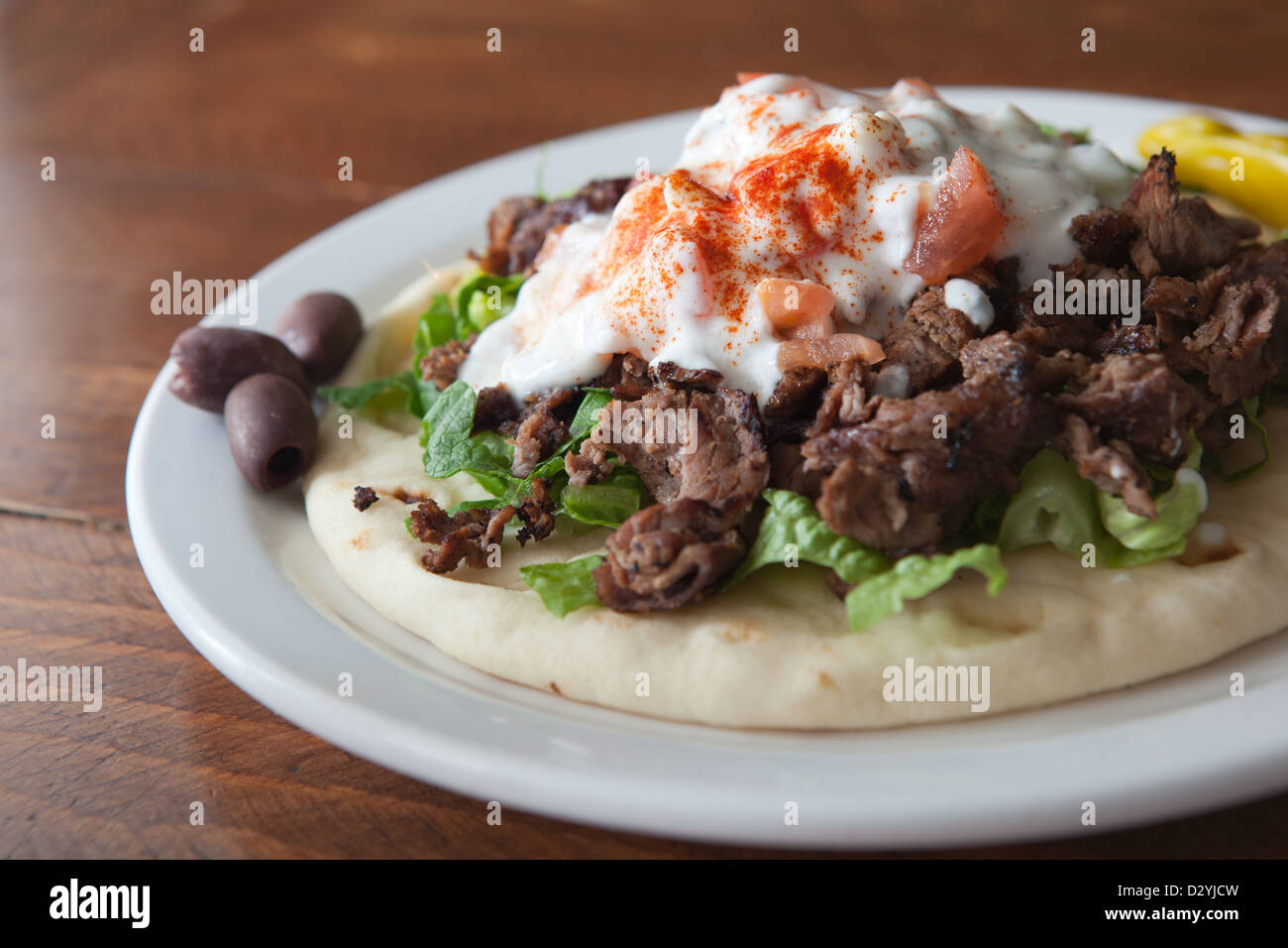 A single serving of Mediterranean style, home made lamb gyro, topped with lettuce, tahini sauce
