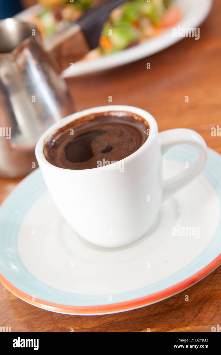 Demitasse cup of rich and robust Turkish or Arabic coffee served with metal carafe. Stock Photo