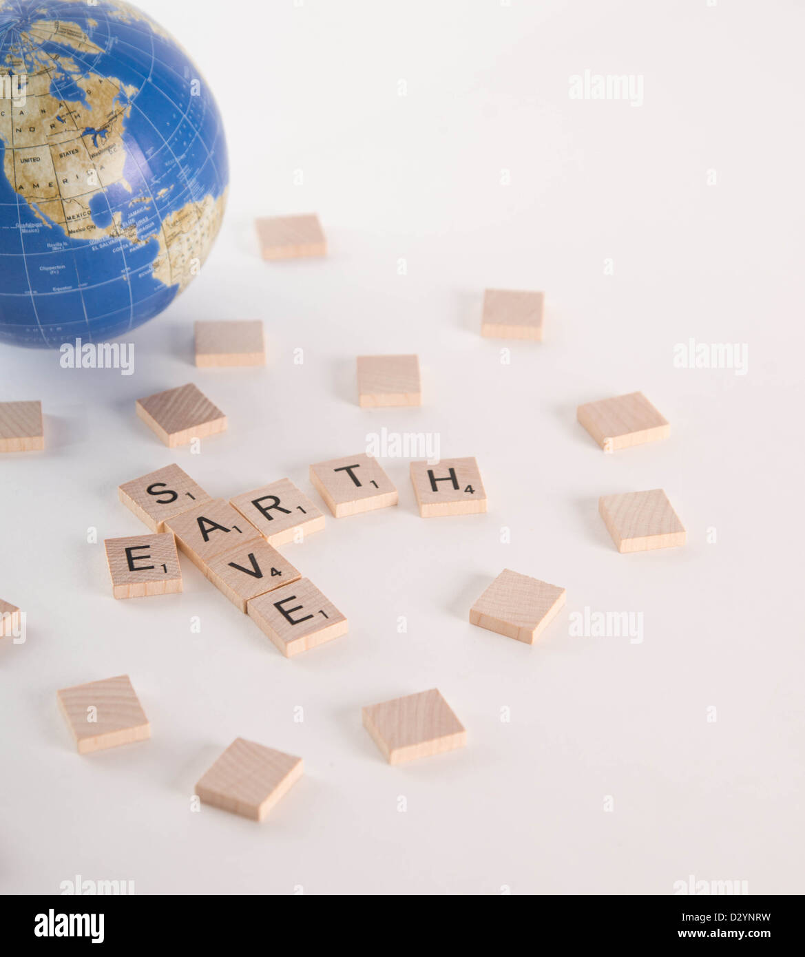 Save Earth concept spelled out in Scrabble letters with out of focus world globe in the background. Isolated on white background Stock Photo