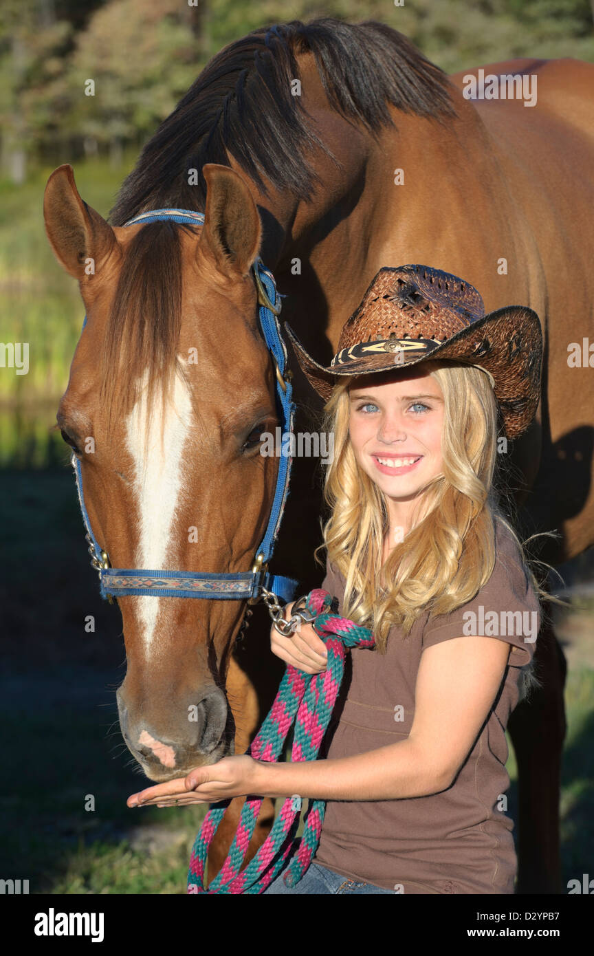 Girl with horse in close up portrait, pretty blond in cowboy hat, summer evening in Pennsylvania, PA, USA. Stock Photo