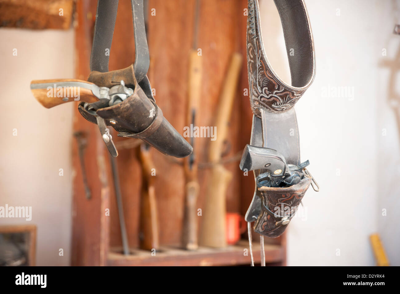 Six shooters hang in holsters at a gun shop at an old west ranch Stock Photo