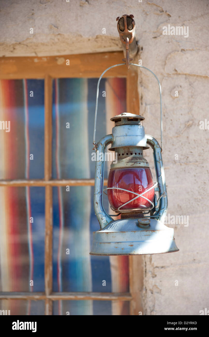 An old red gas lantern hangs near a door at an old west style dude ranch Stock Photo