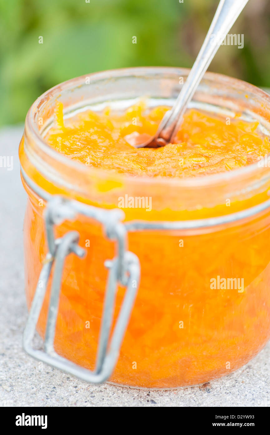 Glass container of carrot marmalade and fresh carrots Stock Photo