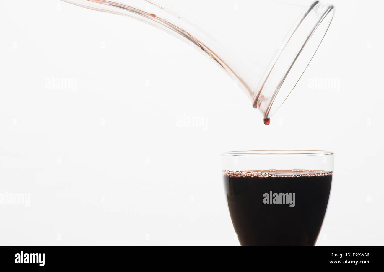 A glass of red wine being filled from a carafe Stock Photo