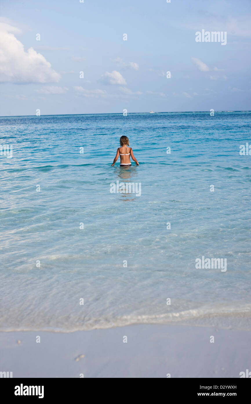 Girl wades out to sea, alone, Kuda Hara, Maldives Stock Photo