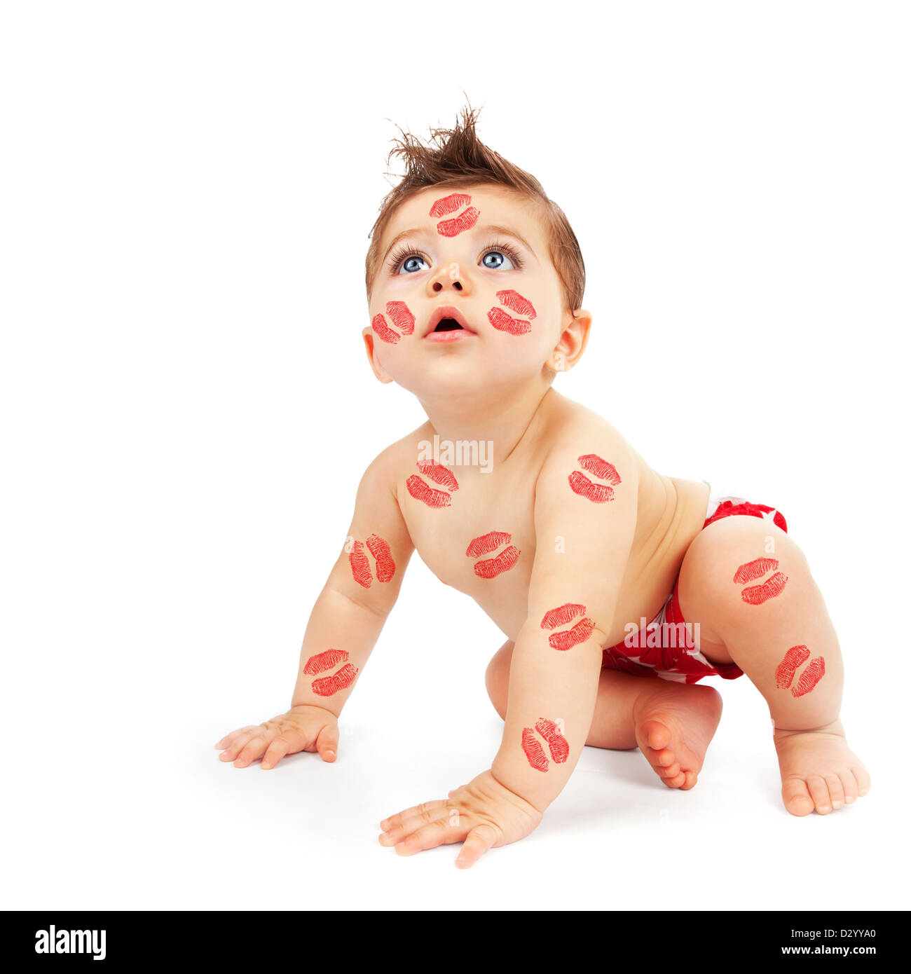 Photo of lovely baby boy try to get up, portrait of cute child isolated on white background, kid covered red lipstick kisses Stock Photo