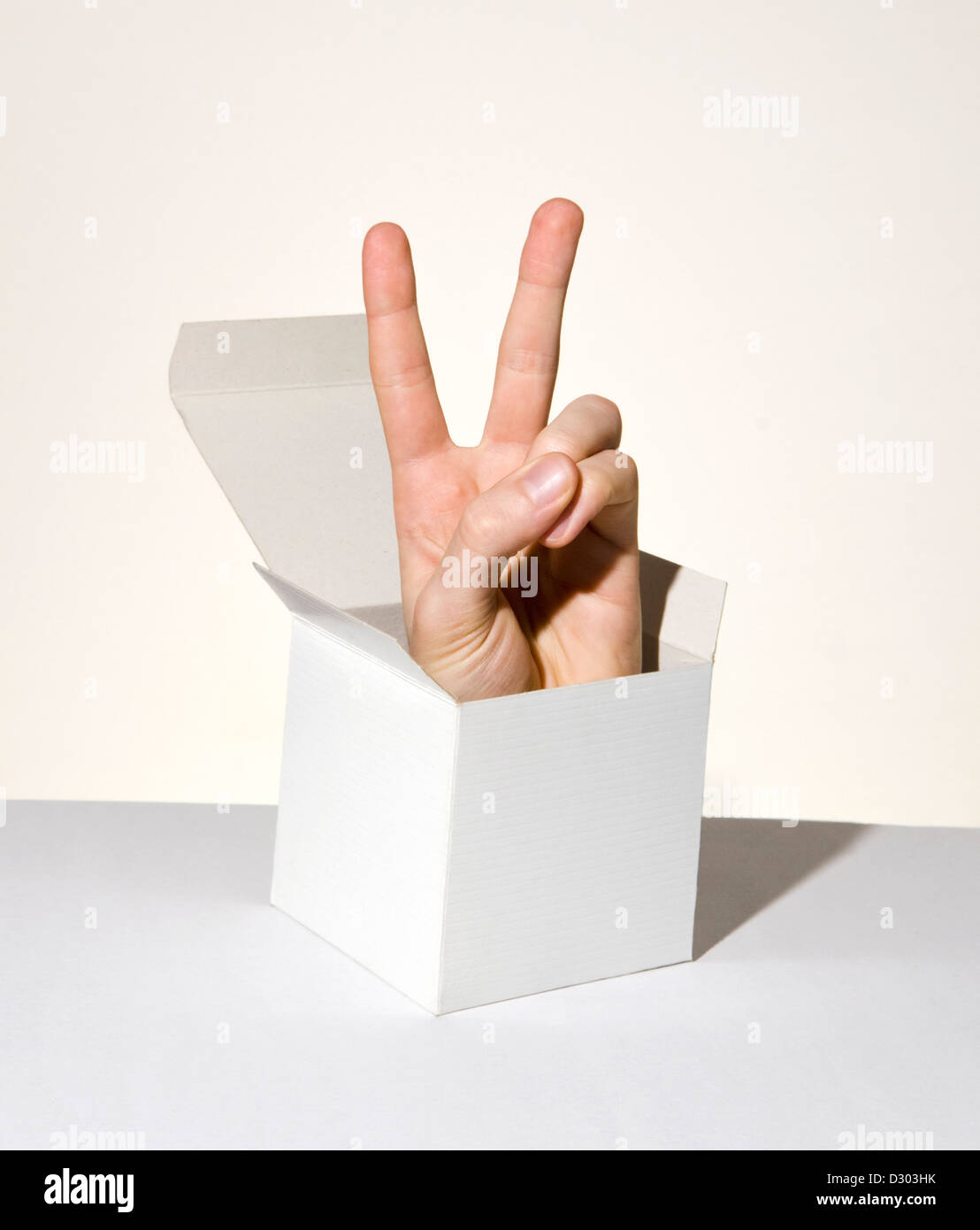 hand popping up from box showing peace sign Stock Photo