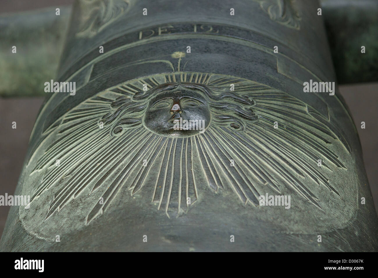 A fragment of the coat of arms of King of France Louis XIV (Sun King) on the old bronze cannon. Stock Photo