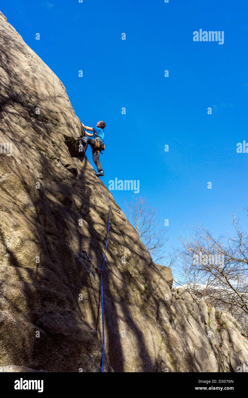 Rock climber in blue on slabby rock face Stock Photo