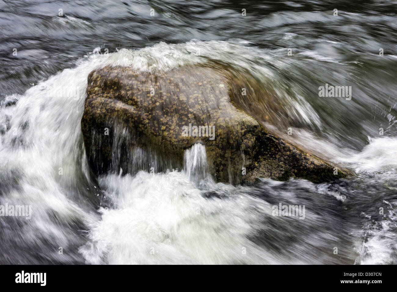 Boulder in stream river with waves washing over Stock Photo - Alamy