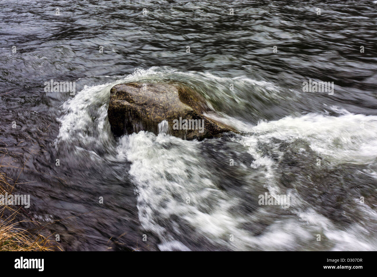 Boulder in stream river with waves washing over Stock Photo - Alamy