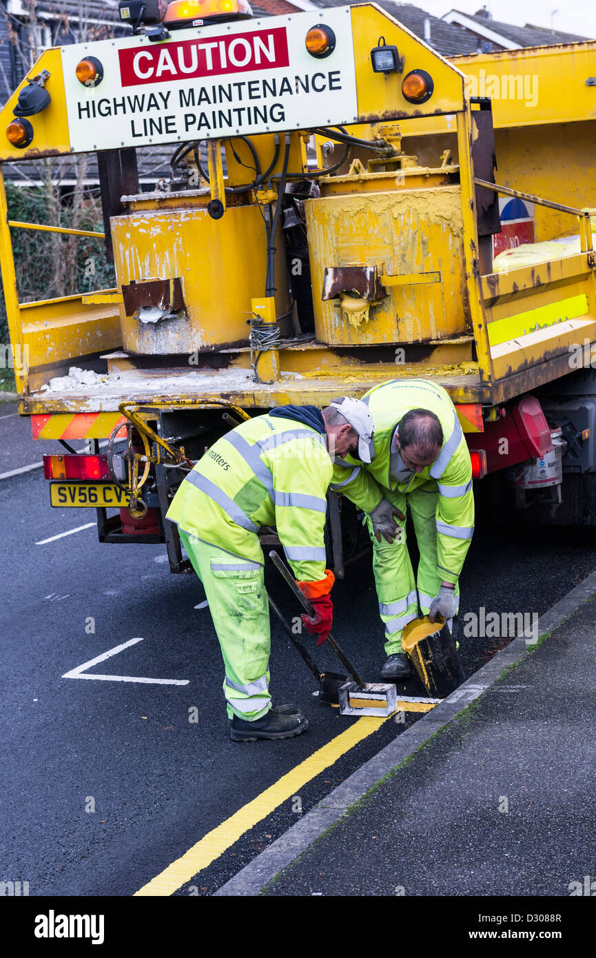Workers on road laying down yellow lines on a road, UK Stock Photo