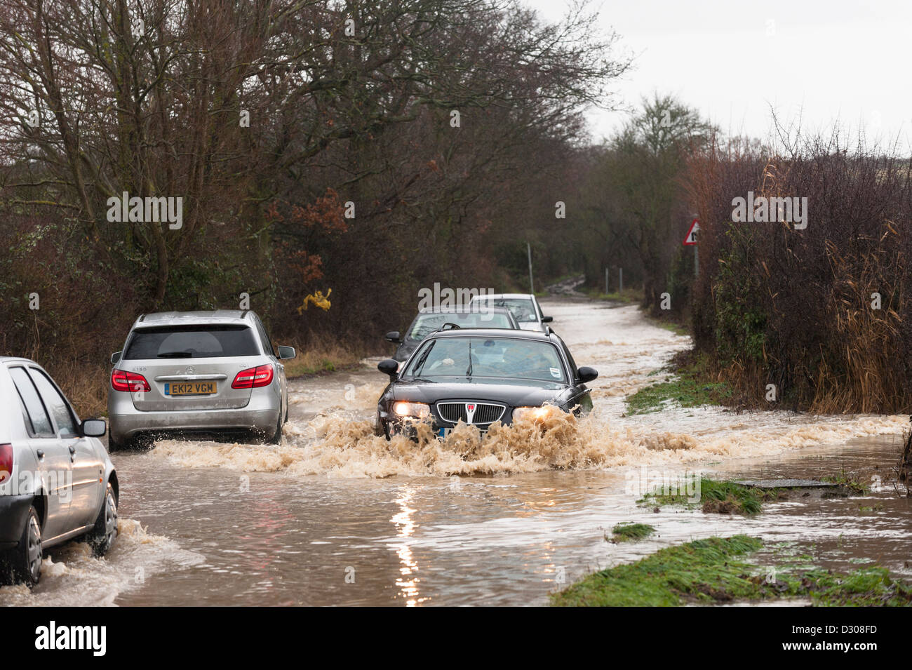 Flooding, UK - Cars struggle to drive along a flooded country road, England, UK Stock Photo