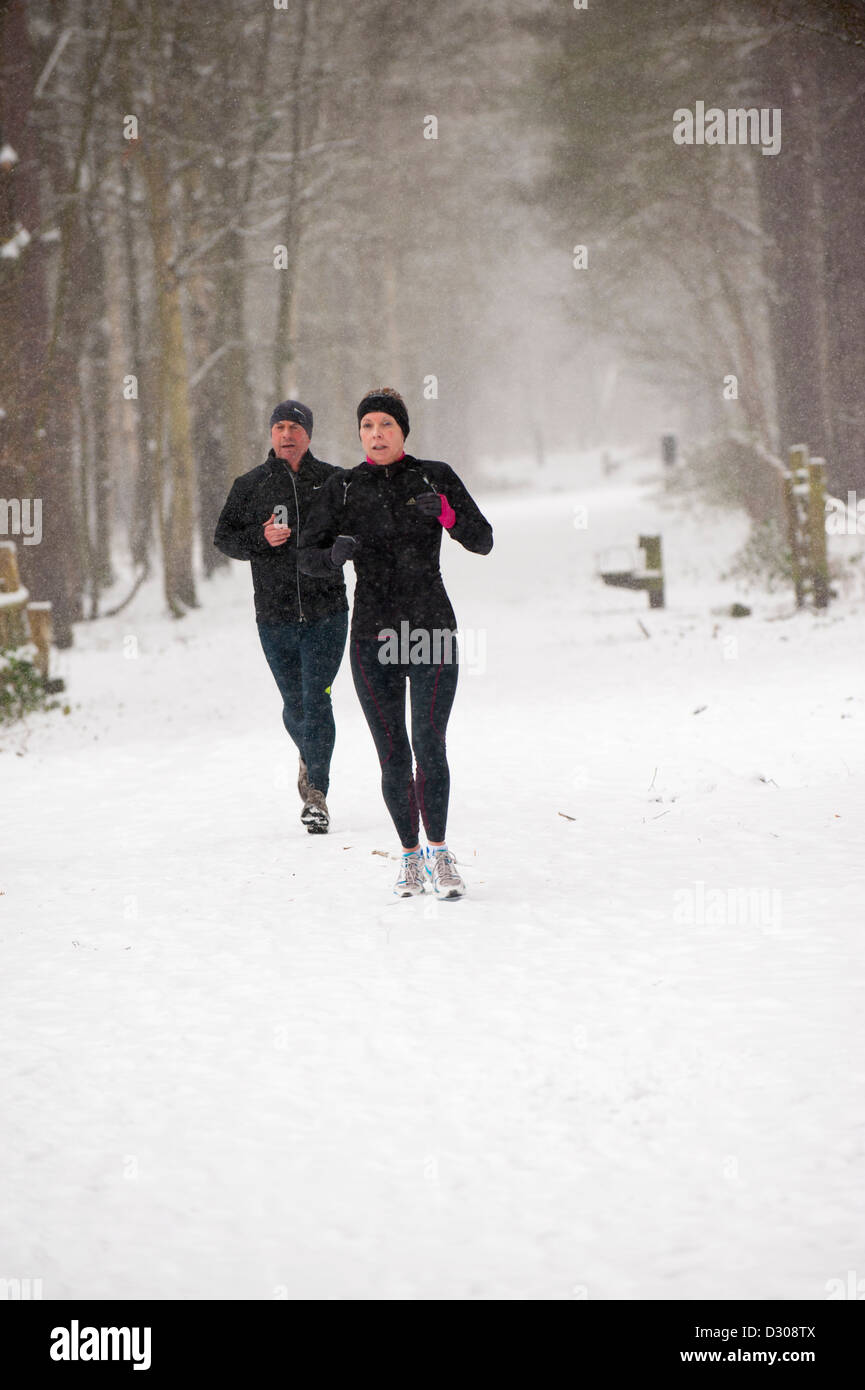 Runners running through heavy snowfall in a park, UK Stock Photo