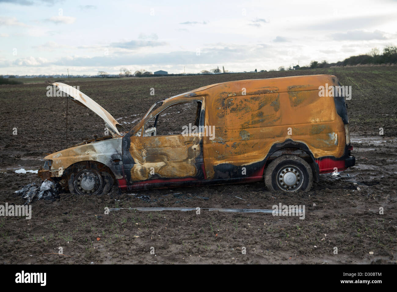 Image of burnt out Ford Escort van in a muddy field on farmland at Battlesbridge, Essex, UK. Stock Photo