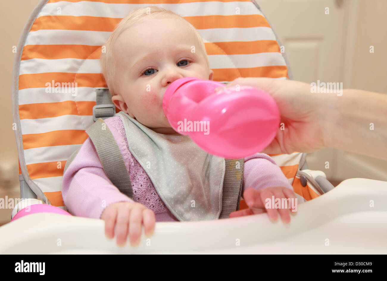 Baby drinking from a bottle in highchair Stock Photo