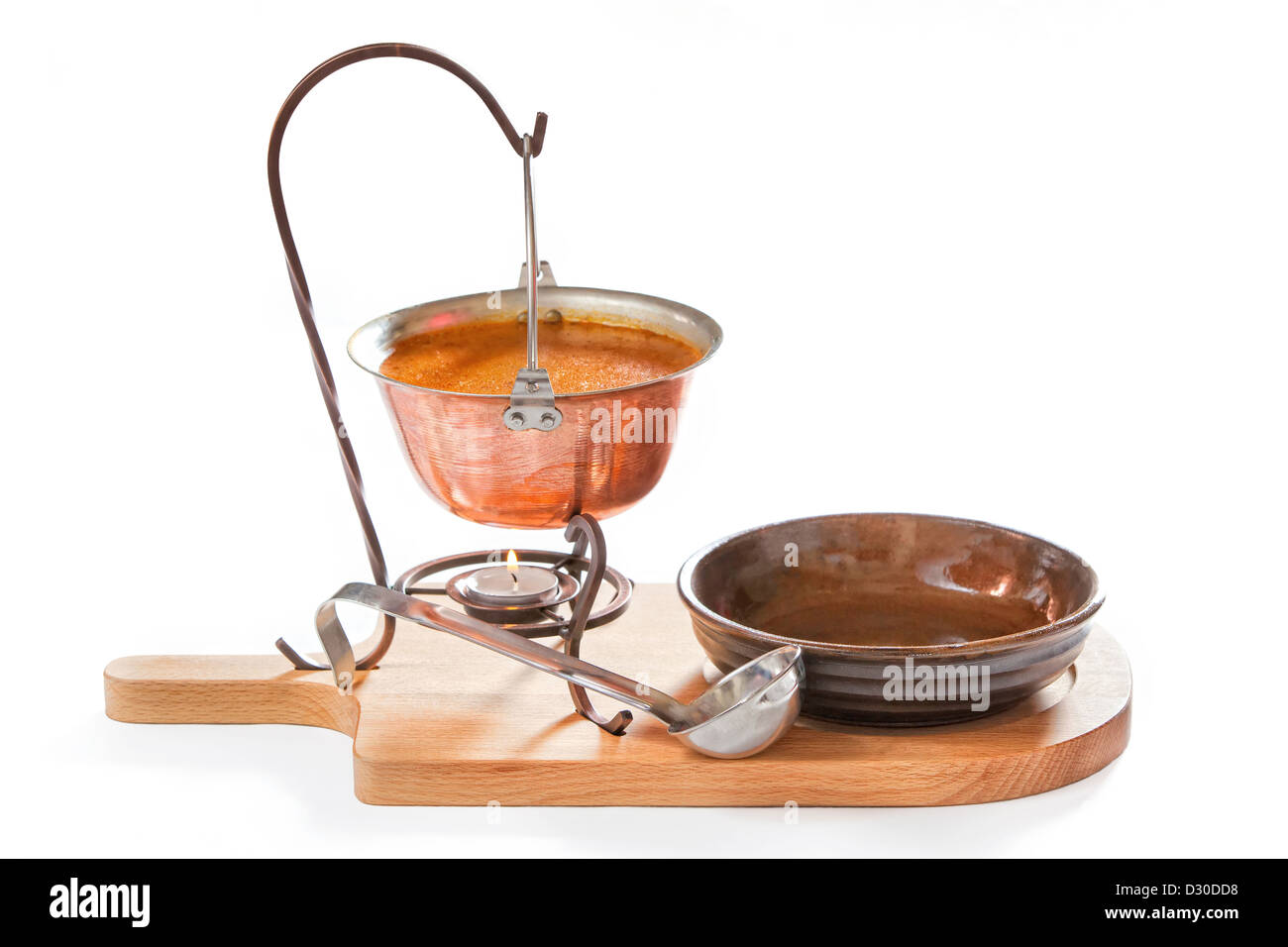 Goulash soup in a pot with ladle and plate on white background Stock Photo