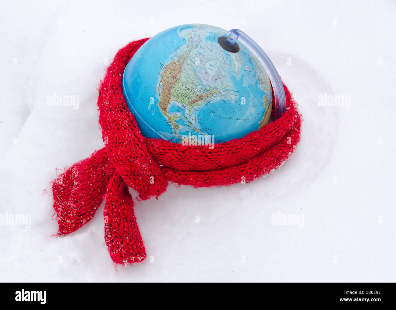 red scarf on earth globe sphere in winter snow snowbank. care of mother earth concept. Stock Photo