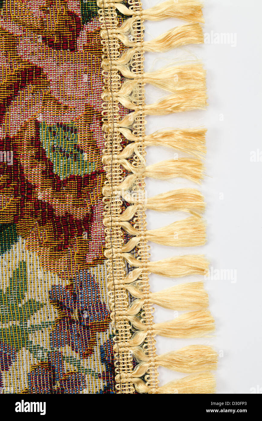 High resolution texture of tapestry with ribbon of tassels along the edge. Over white. Stock Photo