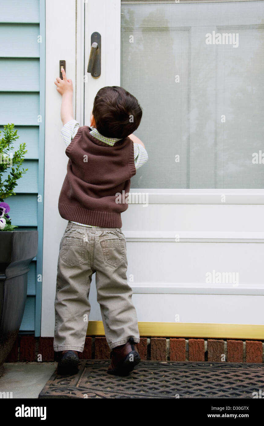 A young boy reaching and ringing a doorbell. Stock Photo