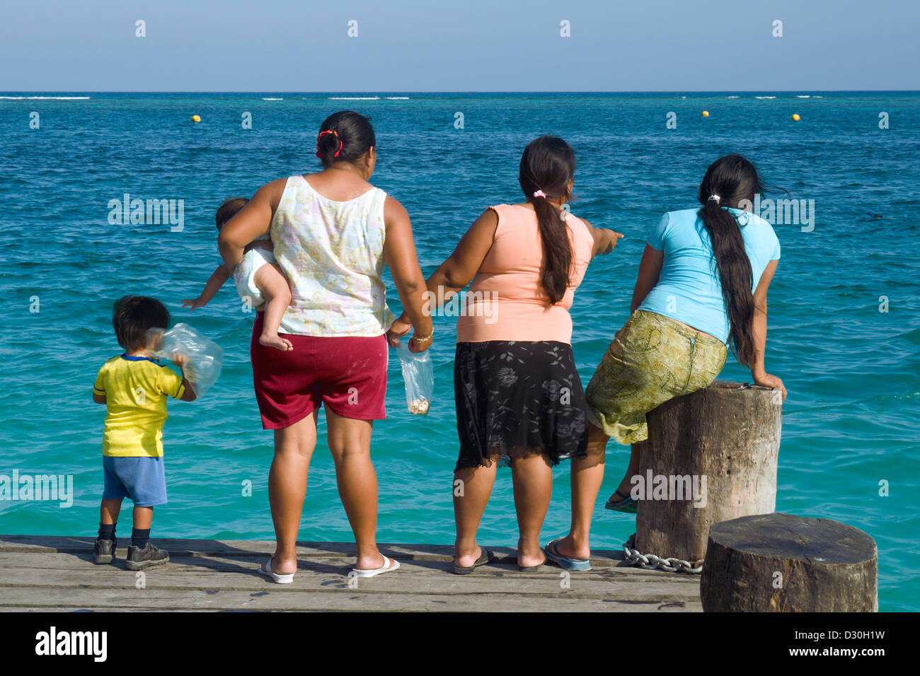 Maya women with children on a dock in Puerto Morelos, Mexico. Stock Photo