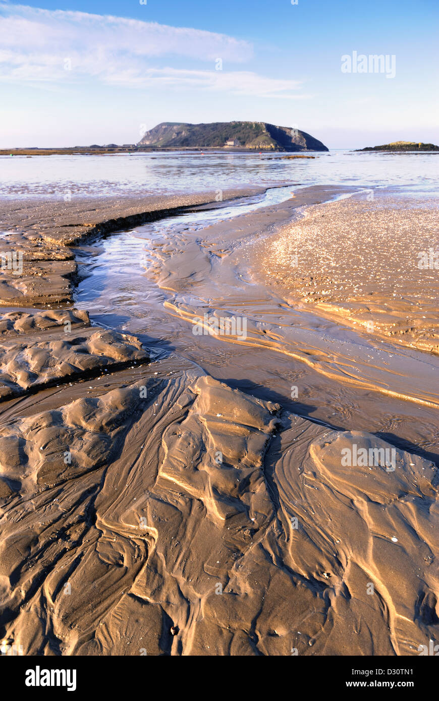 Mud flats at Uphill on the River Severn with drainage channels created by the retreating tide, with Brean Down in the distance. Stock Photo