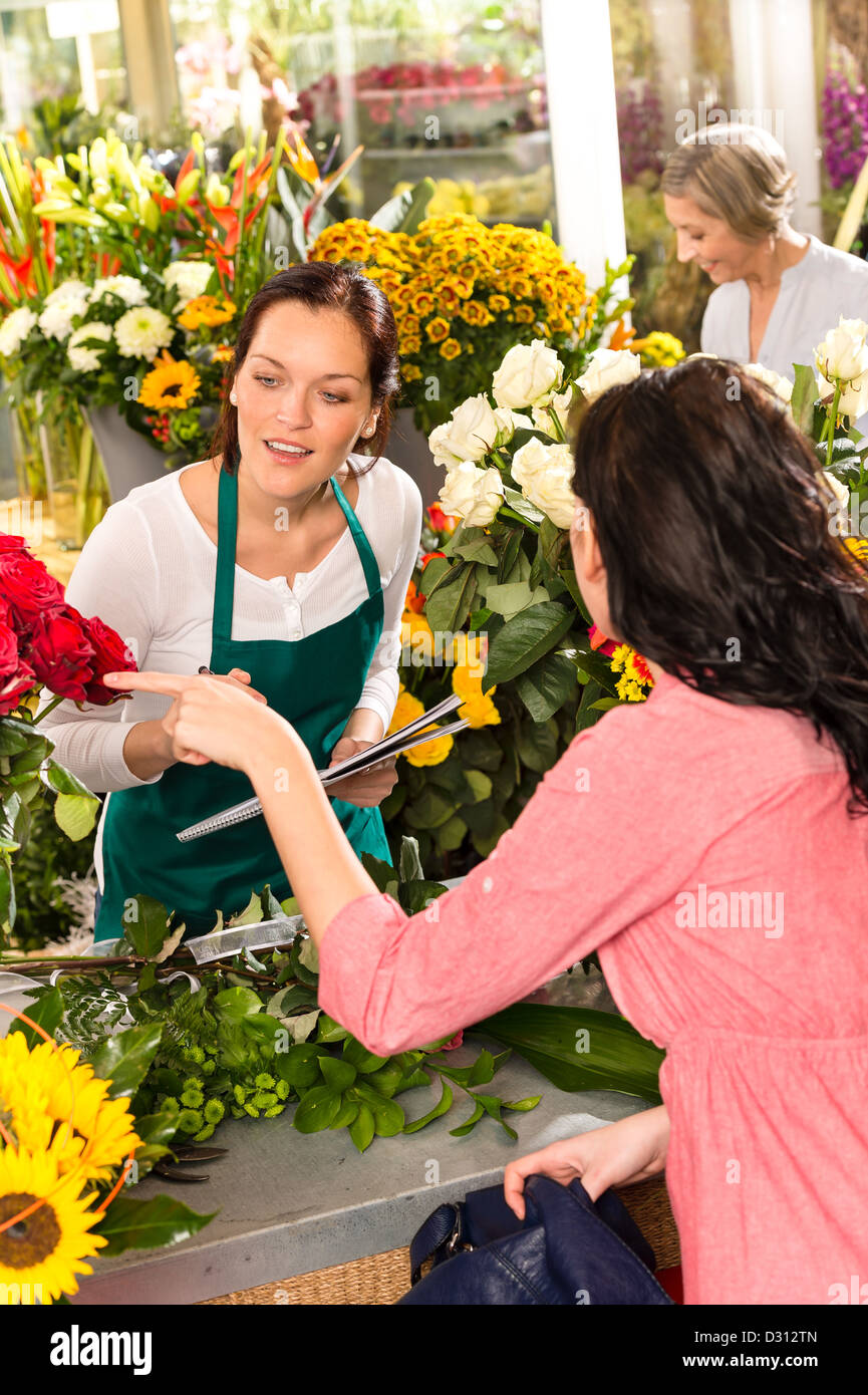 Young florist ordering roses woman customer flower market retail shop