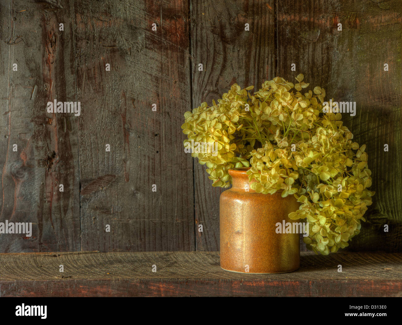 Still life image of dried flowers in rustic vase against weathered
