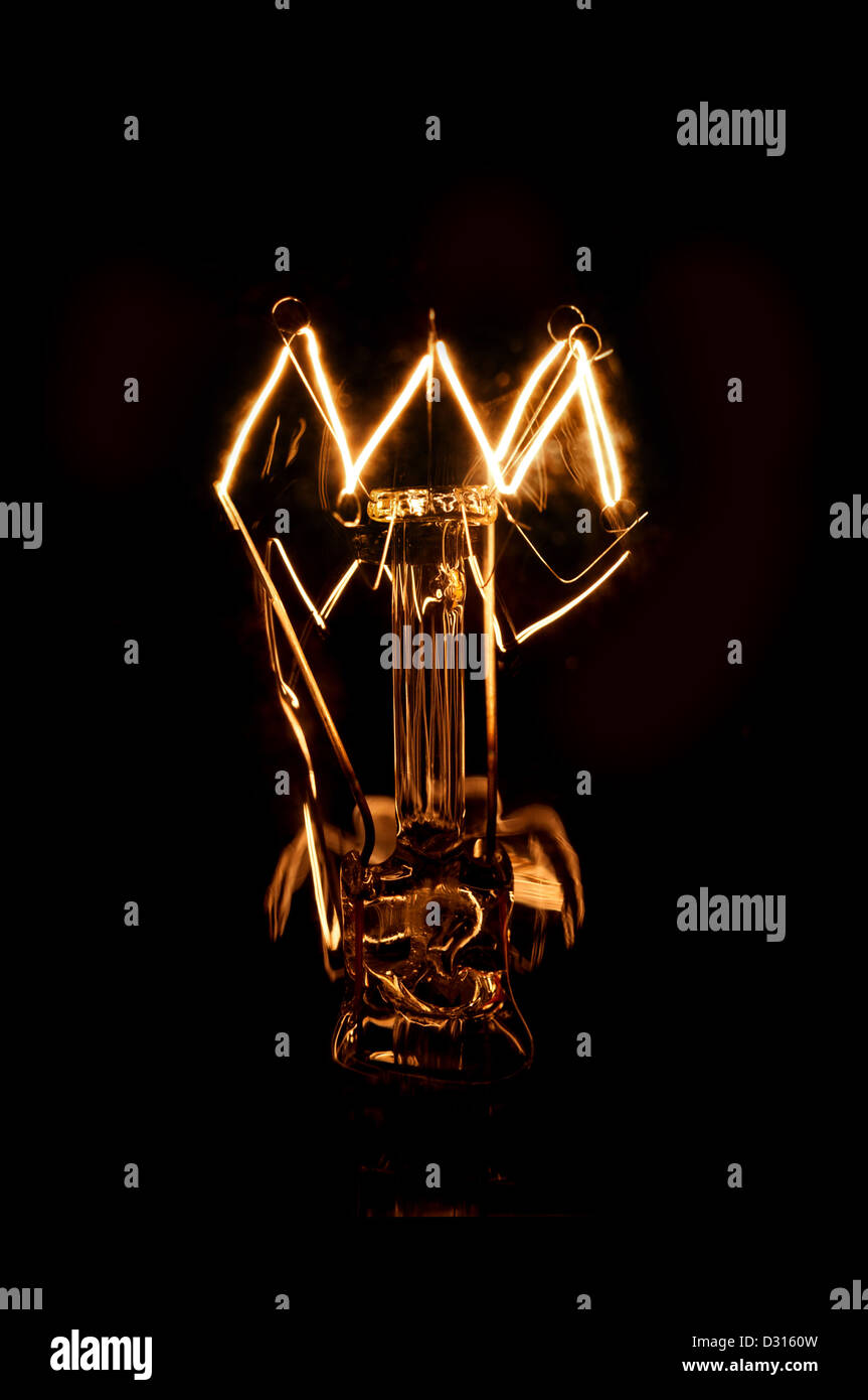 Tungsten Filament of a glowing lightbulb on a dark background Stock