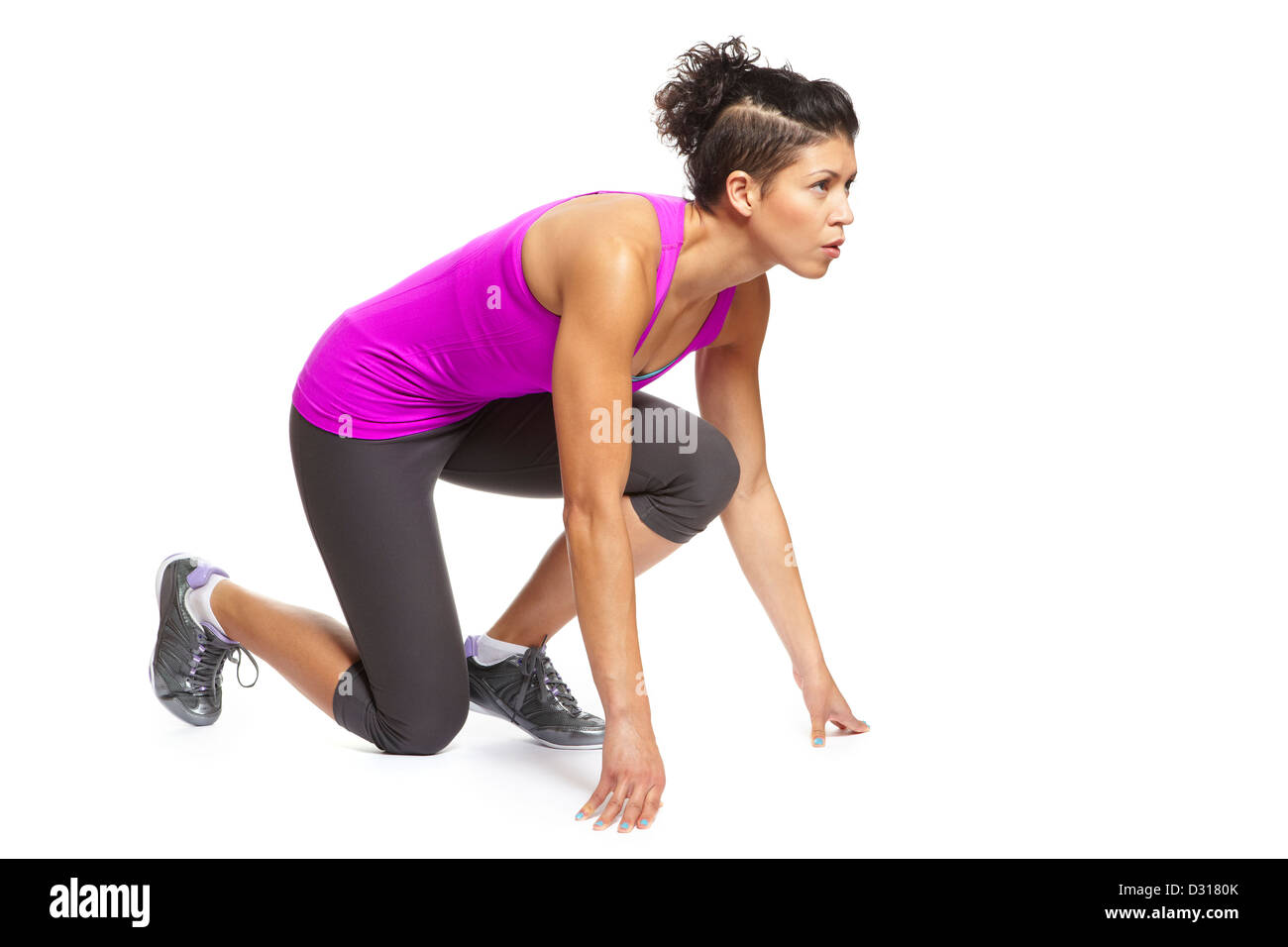 Muscular young woman in starting position and ready to race in sports outfit on white background Stock Photo