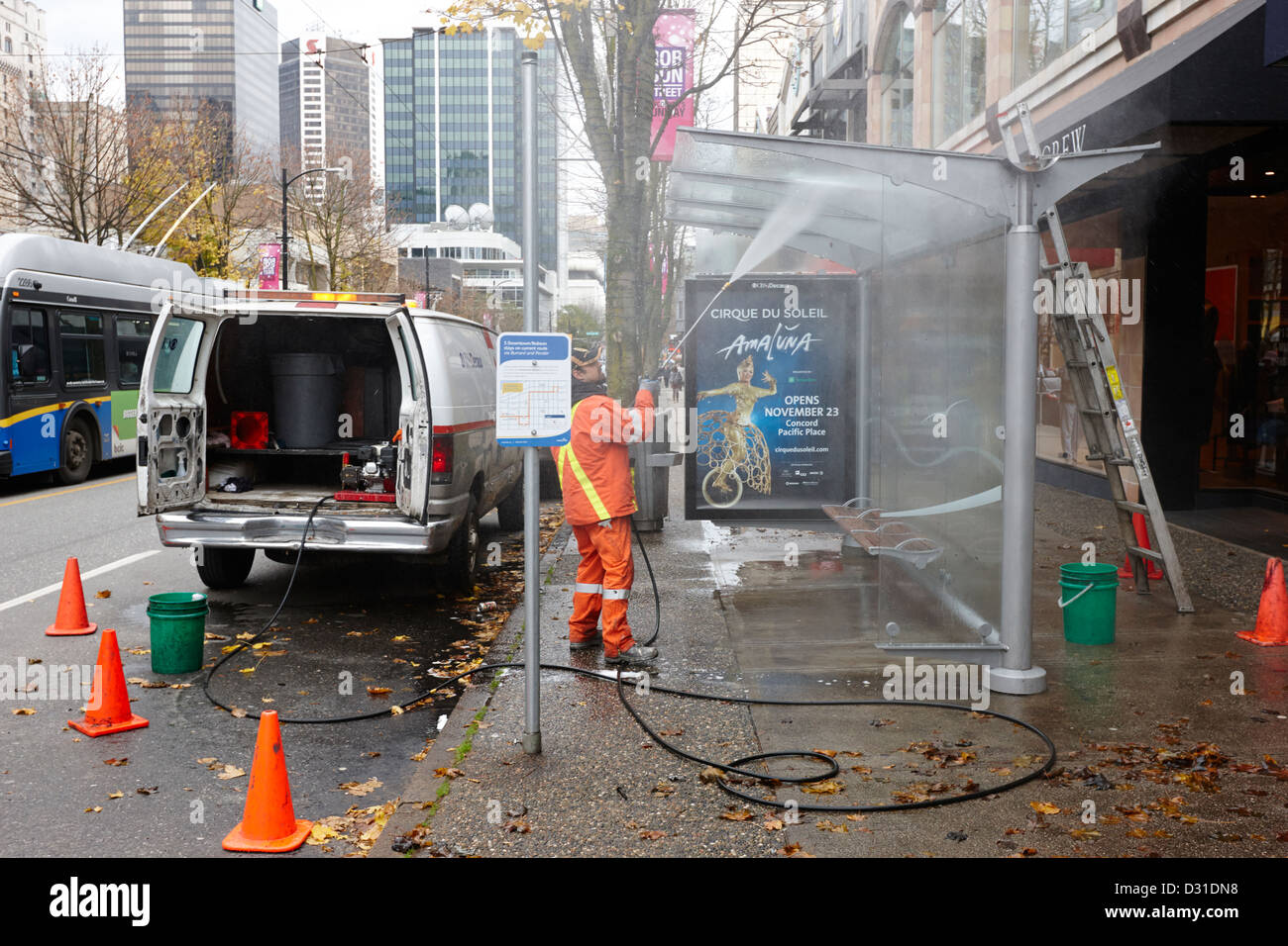 private company cleaning team cleaning a bus shelter with power hose Vancouver BC Canada Stock Photo