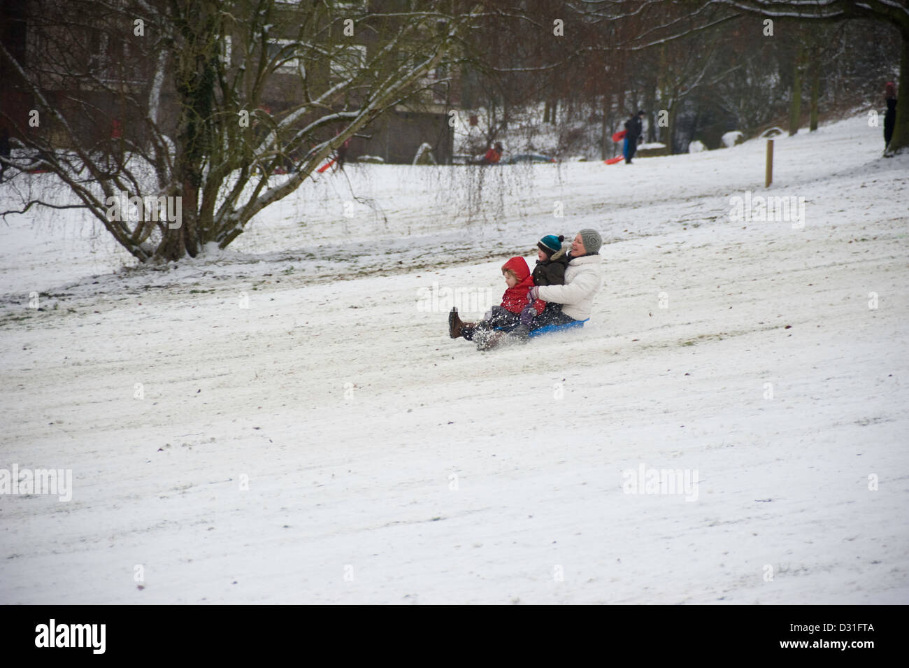 An adult and two children on a toboggan in the snow Stock Photo Alamy