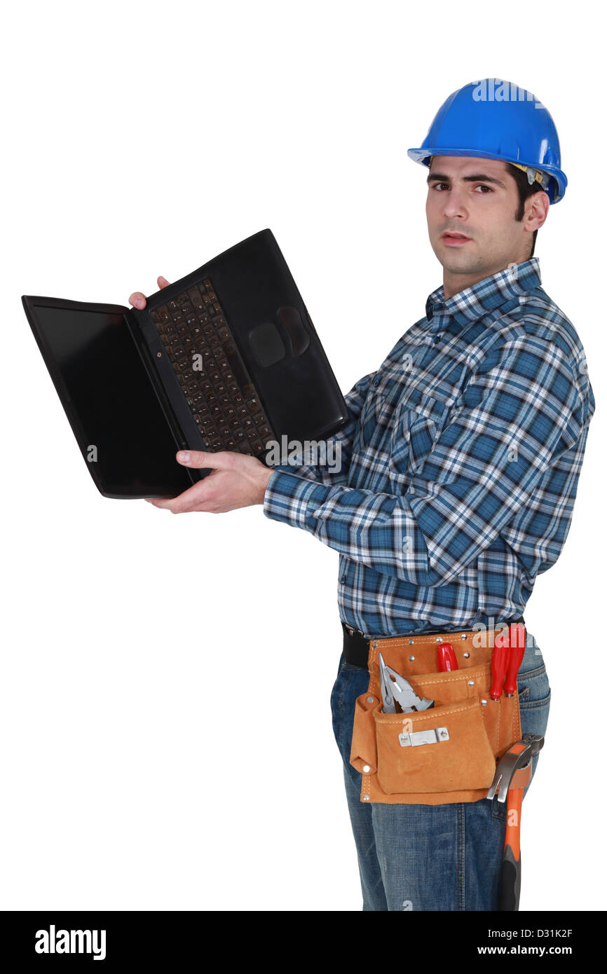 Tradesman looking at the underside of his laptop Stock Photo