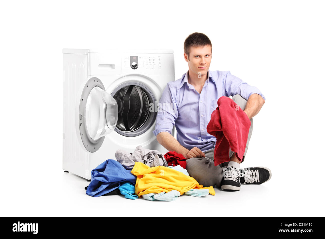 A young male sitting next to a washing machine isolated against white background Stock Photo
