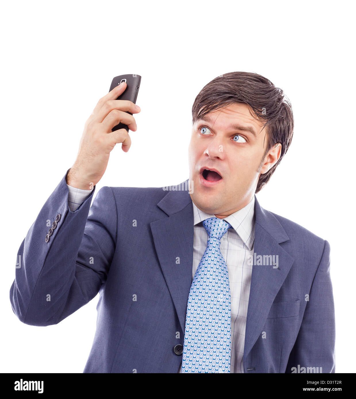 Young businessman holding a mobile phone and looking surprised against white Stock Photo