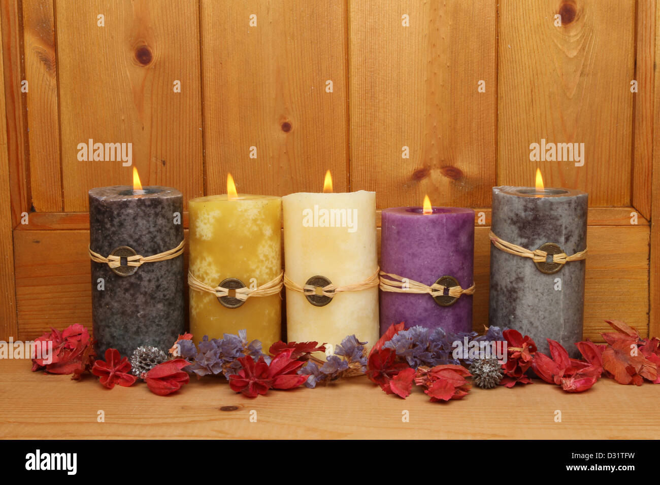 Five burning Feng Shui candles and potpourri against a wooden panel