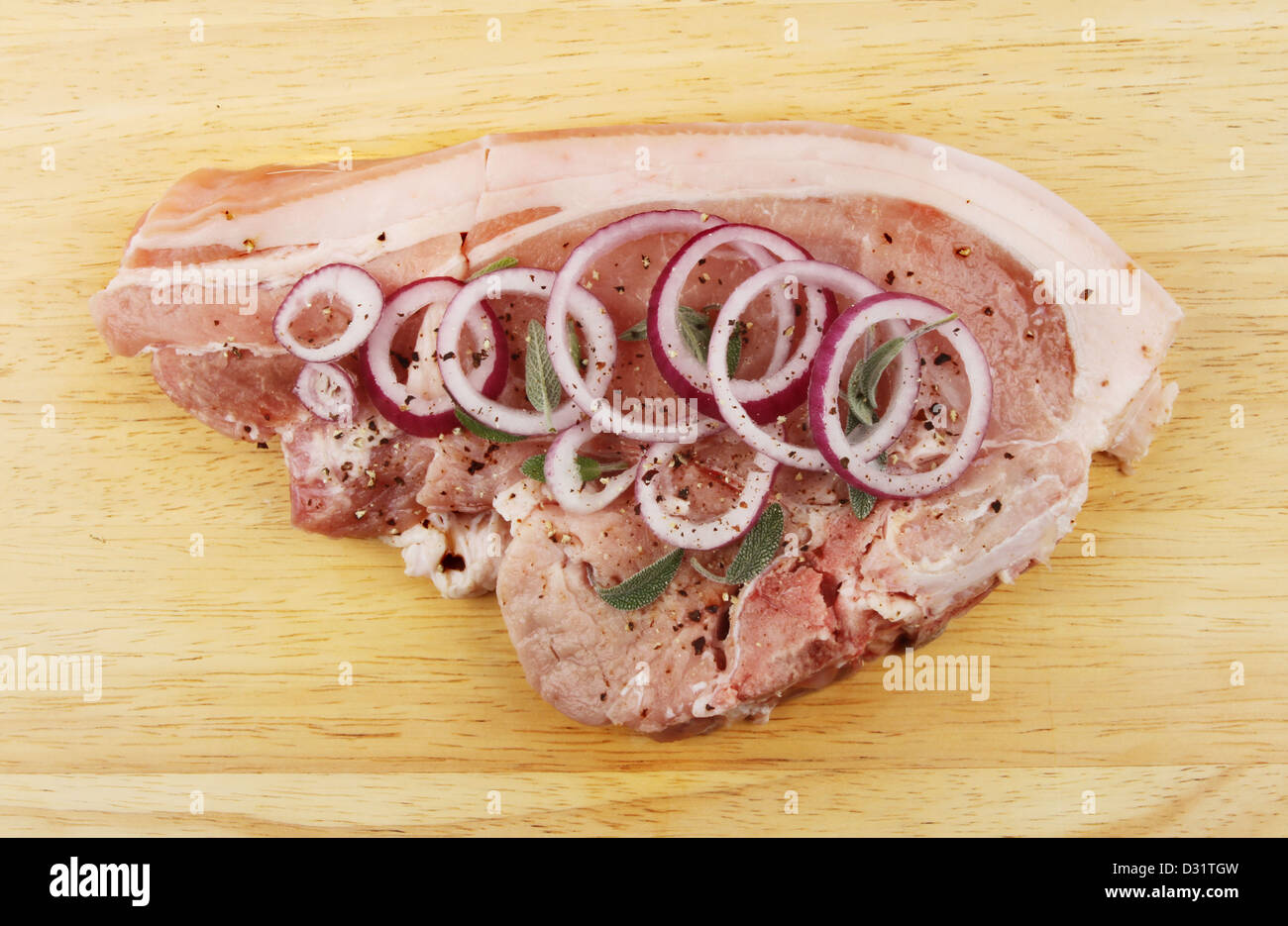 Pork chop with onion, sage and pepper on a wooden board Stock Photo
