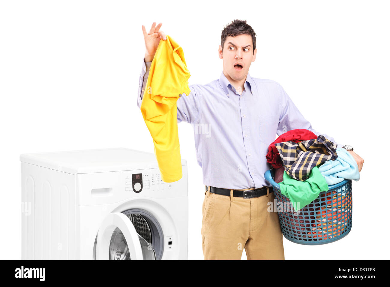 Young man standing next to a washing machine and holding dirty laundry isolated on white background Stock Photo